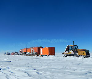 A tractor hauls containers across the ice on a traverse to Aurora Basin