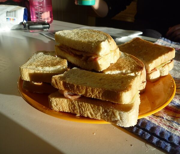 A plate of toasted bacon and cheese sandwiches