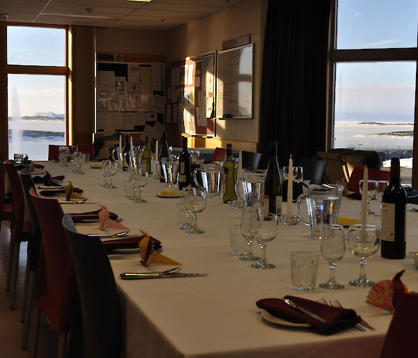 The dinner table set up with individual places and the view through the windows showing sea-ice and icebergs