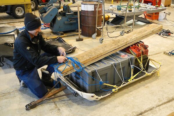 Kelvin ties the gear and the ramps onto the sled