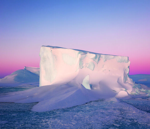 A tabular iceberg against a pink sunset.