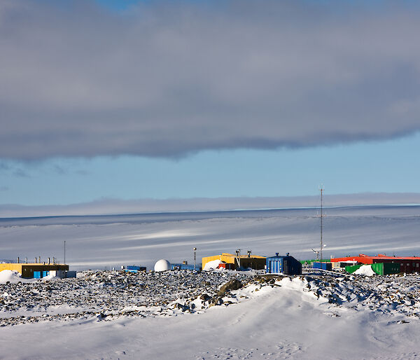 The buildings of Casey station are coloured in reds, yellows and greens and surrounded by ice.