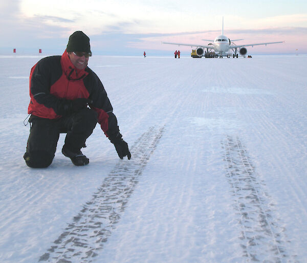 Runway Construction Supervisor pointing out tyre marks on the ice runway — A319 in background.