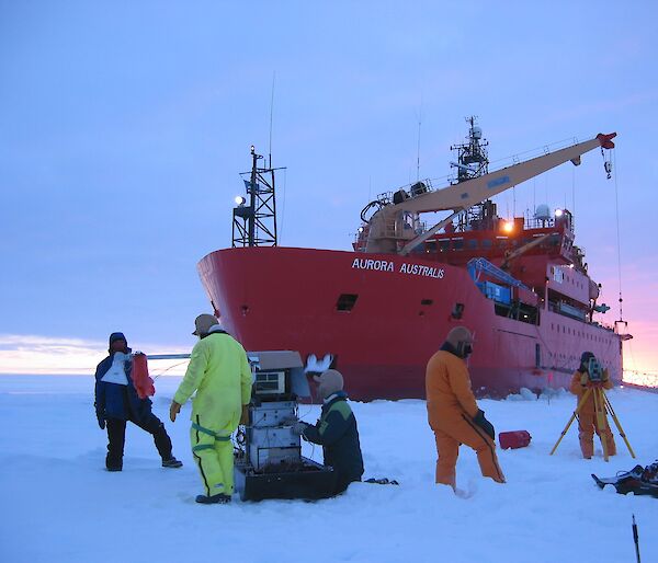 Several scientists working on sea ice in front of the ice breaker, Aurora Australis.