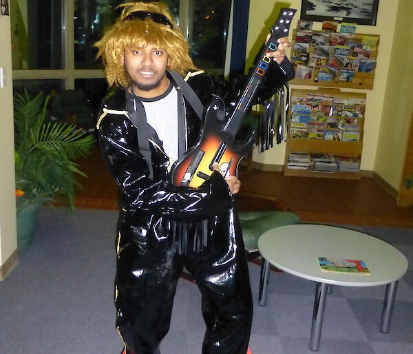 Abrar in a black leather Elvis suit in a classic Guitar hero pose