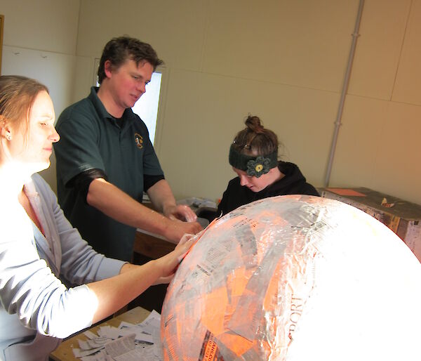 The beginning of the piñata with people and a ball of papier mache