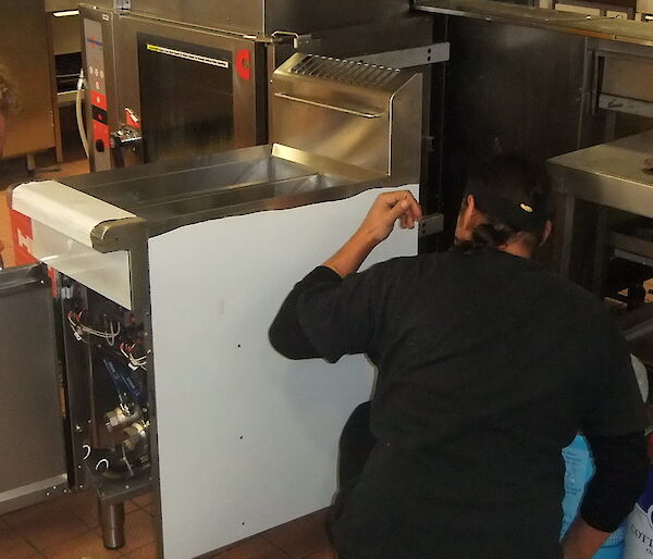 Two expeditioners installing large industrial kitchen equipment