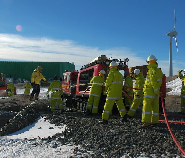 Mawson fire exercise showing a fire truck and expeditioners if firefighting uniforms during the training