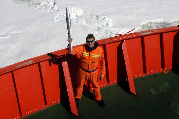 Expeditioner standing on the deck of the ship, holding the Queen’s Baton