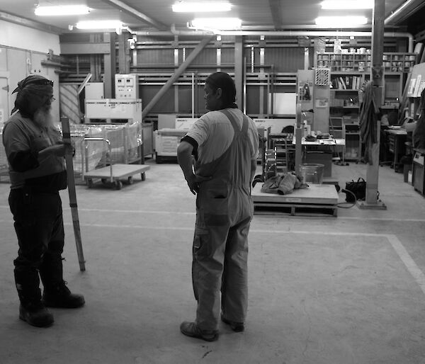 Two expeditioners standing in an empty storehouse