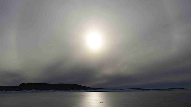 View across the smooth fast ice to solar halo over the land