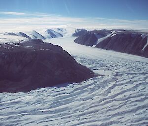 Aerial photo of the ice of the Lambert Glacier moving between two landforms