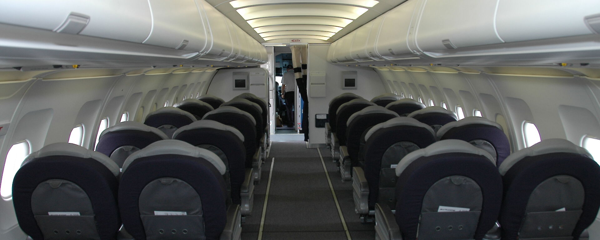 Rows of seats inside a small plane, three on each side with a row in the middle