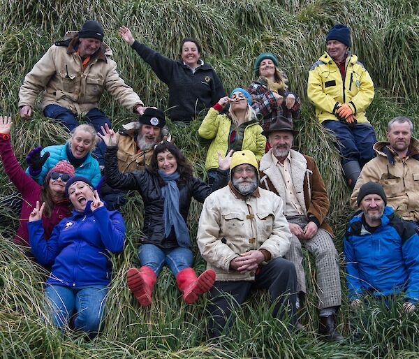 A team of seven men and seven women sit in the green tussock
