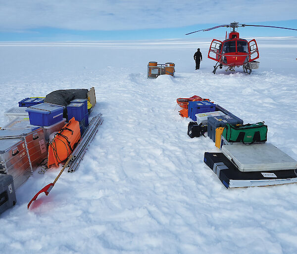 Equipment and a helicopter on a snow-covered glacier in Antarctica.