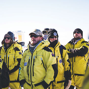 Group of expeditioners wearing yellow Antarctic clothing.