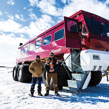 Two expeditioners posing in front of large omnibus.
