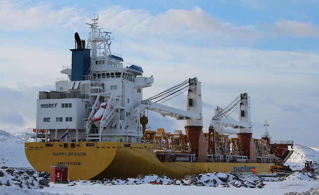 Large yellow and white cargo ship sitting in a snow covered dock