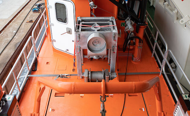 A small orange boat on board a large orange icebreaker ship.