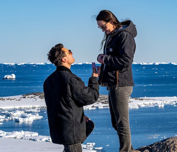 A man kneels down proposing to a woman