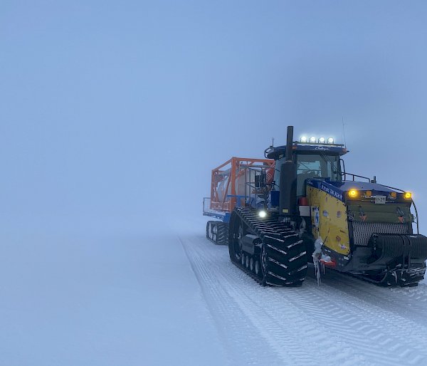 A Challenger tractor towing a flatbed. The cloudy sky appears to merge seamlessly with the snowy ground