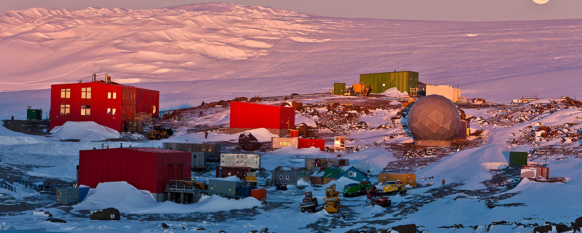 A view of Mawson Station with the Moon visible above the distant horizon