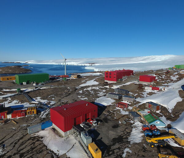 A cluster of brightly coloured buildings with the sea in the background and snow covered hills
