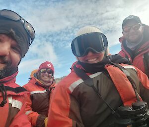 A selfie of four expeditioners in immersion suits on an IRB