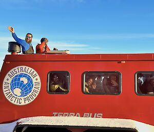 Expeditioners wave goodbye from the hatch out the top of transport bus