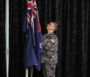 A woman in a military outfit raises an Australian flag