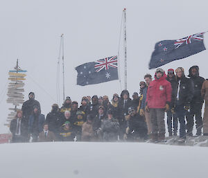 The Casey winter team commemorating the Anzacs in front of flags and Casey sign