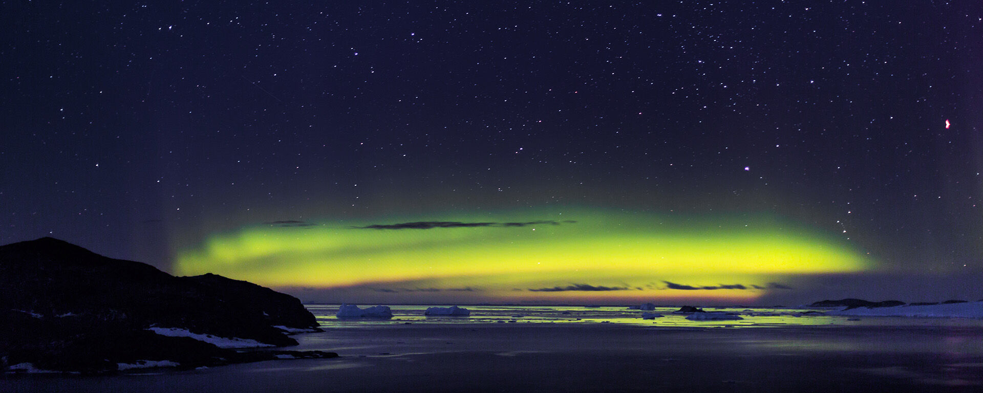 Aurora Australis green lights over the coastline