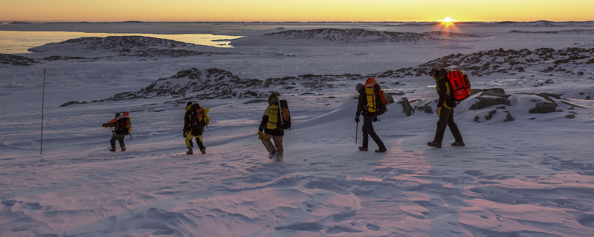 A row of expeditioners in an icy landscape.