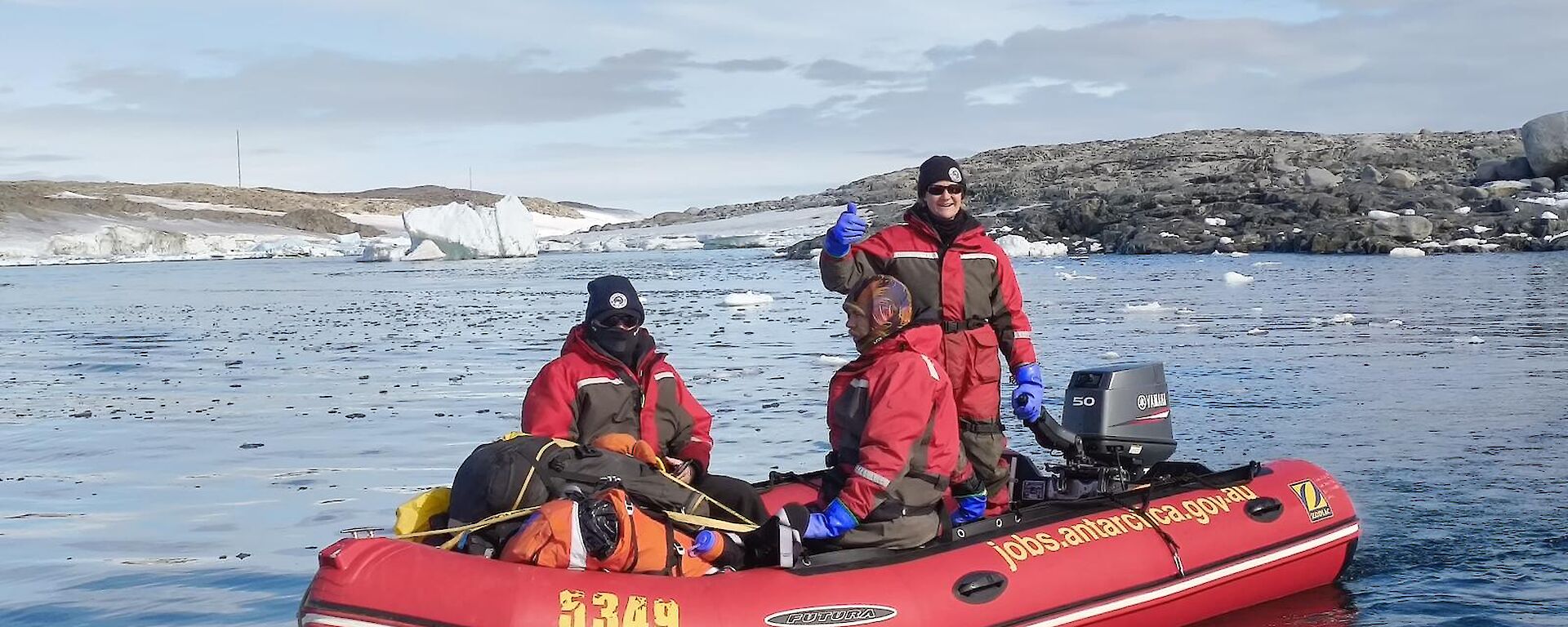 Ron and two others, dressed in immerison suits in an IRB, water and shoreline in the background