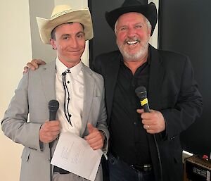Josh and Ron dressed in suit jackets and cowboy hats, holding microphones and ready to present for the Charity Auction