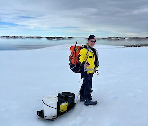 Ron with his survival backpack in the foreground, snow and ocean views in the background