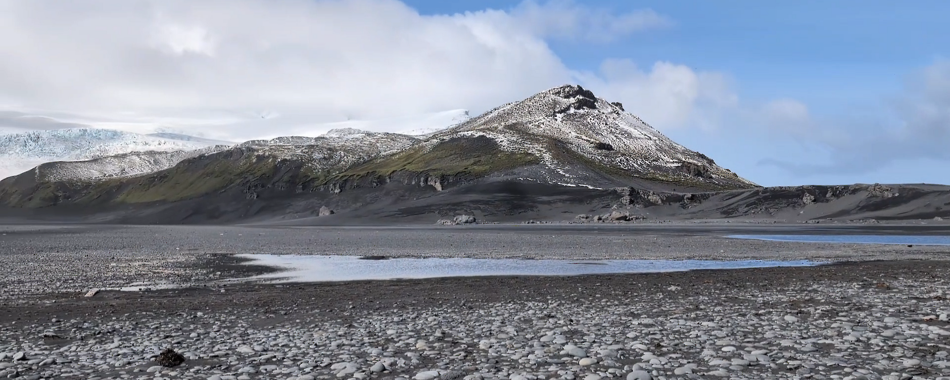 A rocky peak rises into a blue sky with som elow cloud behind.