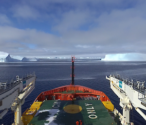 The red bow of a shop with a green open space is shown in the foreground of an expanse of iceberg filled ocean