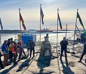 A ceremony with flags in the background and the ship