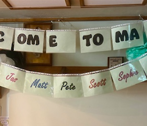 A sign that says "Welcome to Macca" with the names of 10 people underneath