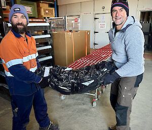 Two expeditioners handling a wrapped cargo consignment (destined for return to Australia) in Mawson's Greenstore