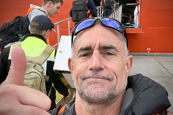 A selfie of an expeditioner giving the 'thumbs up' as others board the RSV Nuyina at Hobart's Macquarie Wharf