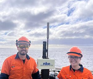 Two Bureau of Meteorology expeditioners standing next to a CSIRO ARGO float on the helo deck of Nuyina.