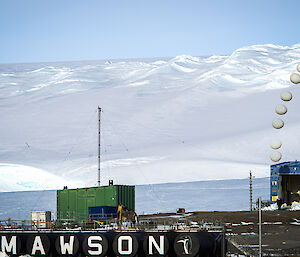 A time-lapse picture of a weather balloon release showing a balloon ascending into the sky, with the Mawson sign in the foreground.