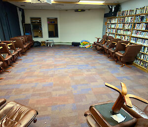 a large room containing multiple chairs, DVDs and VHS videos - with a projector and screen