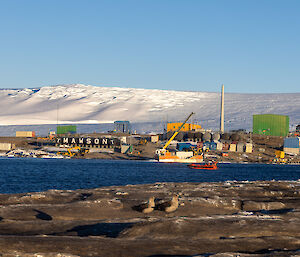 A distant view of Mawson station from West Arm - with skuas on the rocks in the foreground