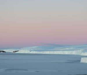 The view from Mawson station looking eastwards - ice shelves and sea ice into the distance, with sunset hues of pink and purple