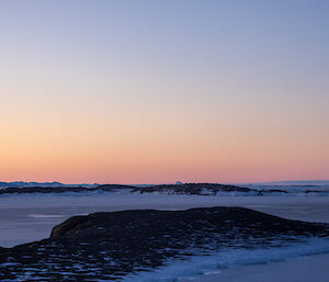 The view from Mawson station looking westwards - West Arm and sea ice into the distance, with sunset hues of pink and purple