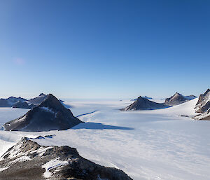 A picture of various brown and jagged rocky outcrops on the plateau behind Mawson