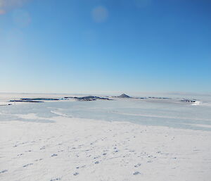 a picture of a blue ice plateau, overlooking Mawson Station with sea ice and islands in the background